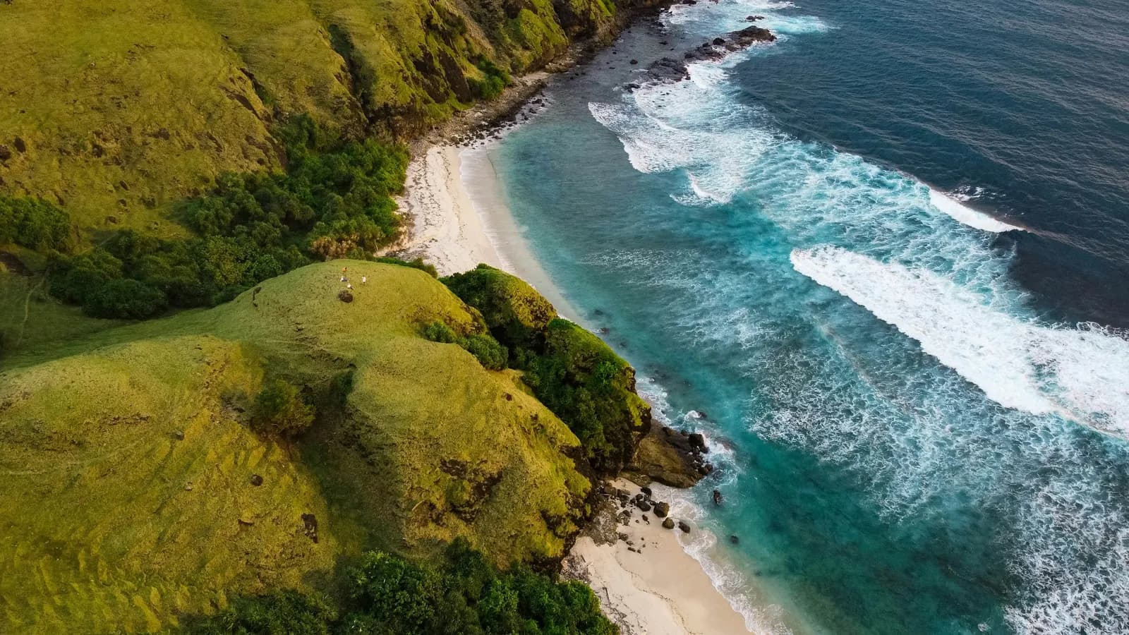 Groene kustheuvels en een baai met wit zand op Lombok, Indonesië
